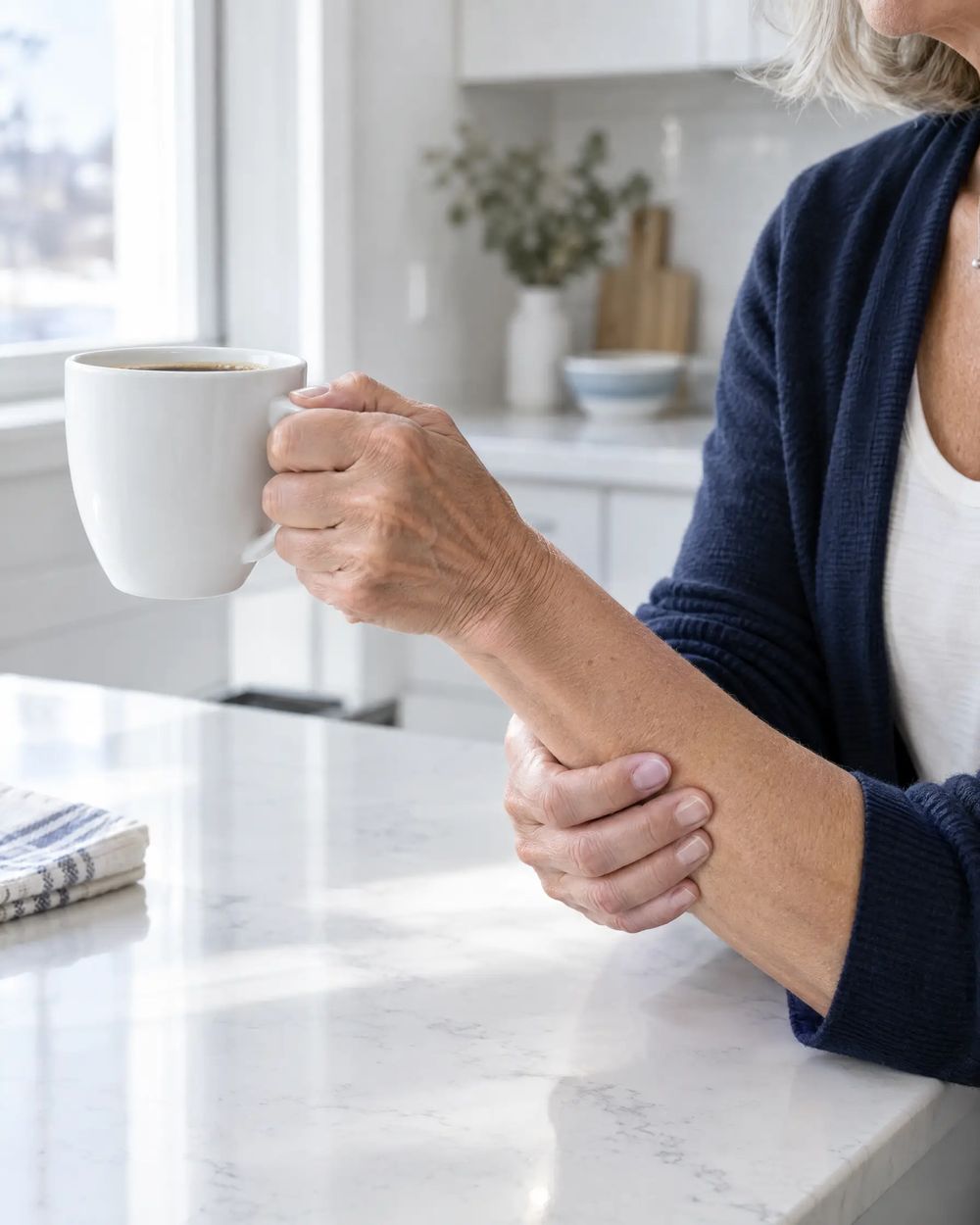 Mains d'une femme qui soulève avec peine une tasse de café